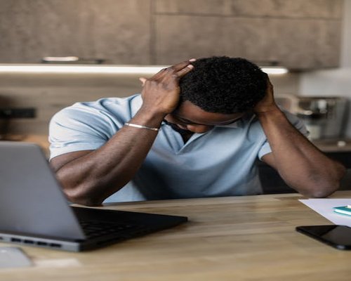 Person working on laptop feeling overwhelmed